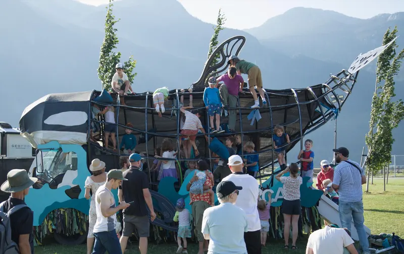 The Orcar packed with people on its deck, mountains and open sky behind it