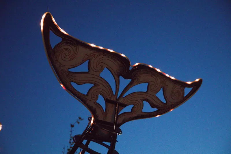 The Orcar's carved wooden tail fluke against a deep blue sky